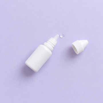 Eye drop bottle on a lavender surface