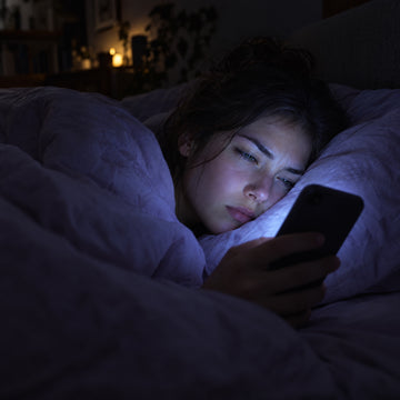 Person reading a phone in bed at night